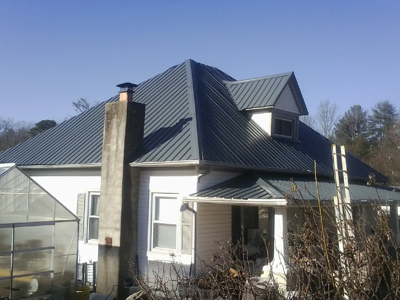 Dark blue standing seam metal roof on a white farmhouse with dormer — Slate & Tile Roof Repair by Roofing Brothers in Tornado