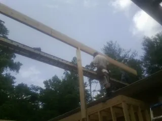 Carpenter setting a ridge beam over a new addition frame — Ice Dam Removal by Roofing Brothers in Tornado