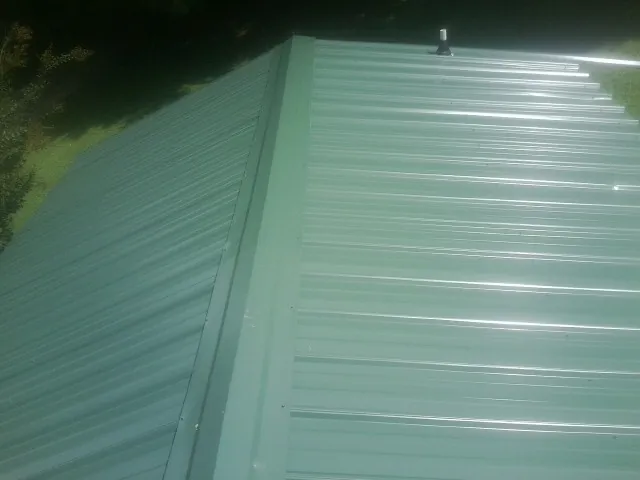 New green metal panels meeting at the ridge of a roof — Flat Roof Repair work by our crew in Tornado