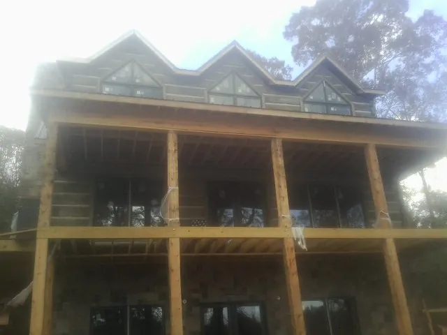 Dormers and porch framing on a large log home under construction — Roof Coating work by our crew in Tornado