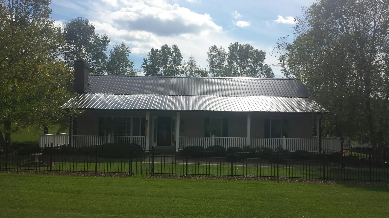 Gray metal roof on a brick ranch with a full width front porch — Gutter Guard Installation work by our crew in Tornado